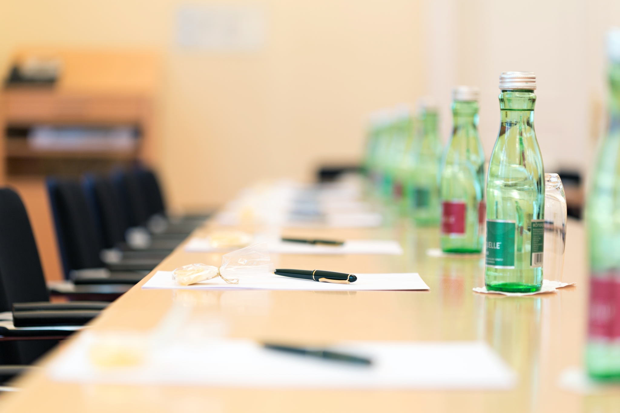 Ein Konferenztisch mit grünen Glasflaschen, Notizblöcken und Stiften für ein Geschäftstreffen.